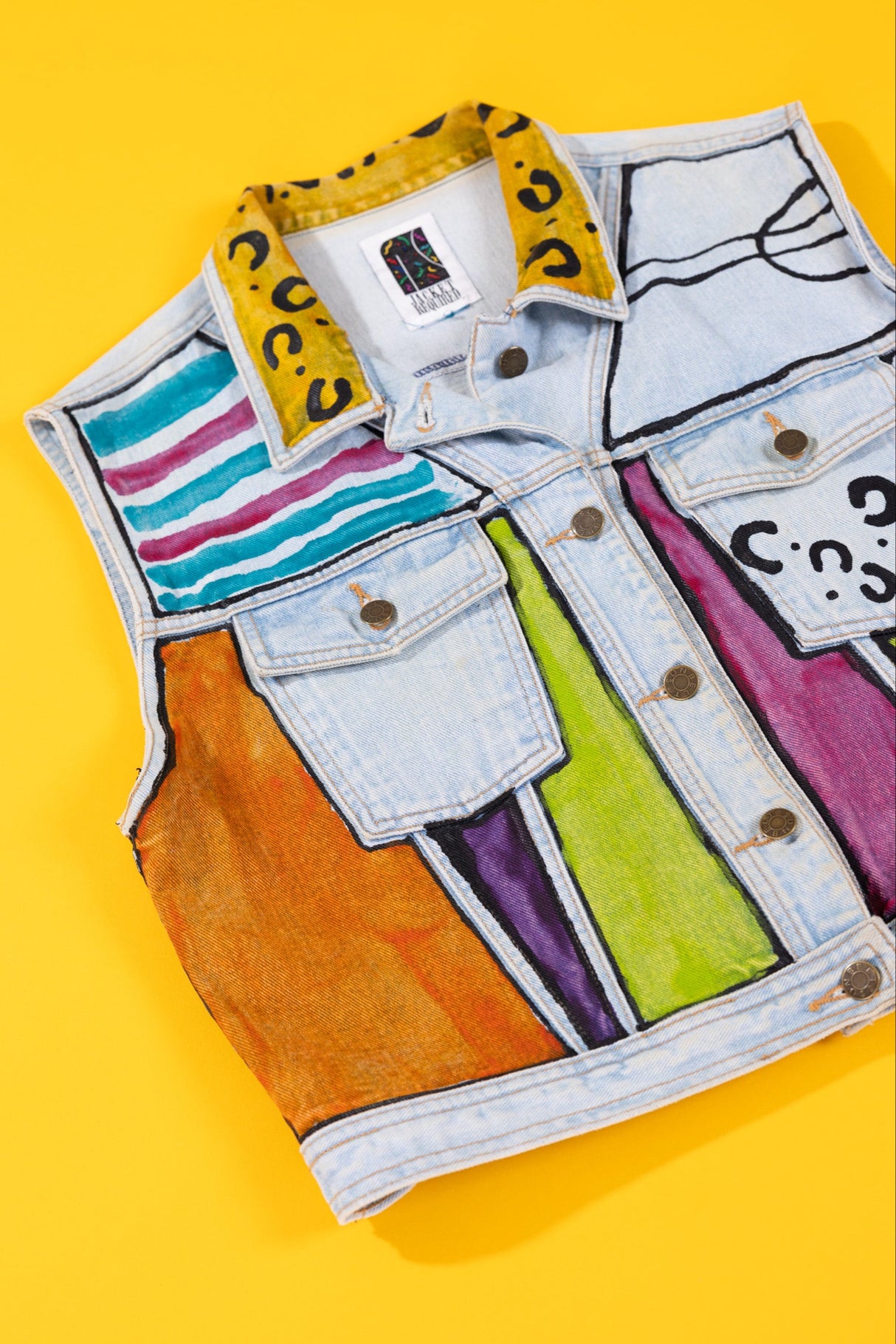 Colorful denim vest with abstract patterns on a yellow background
