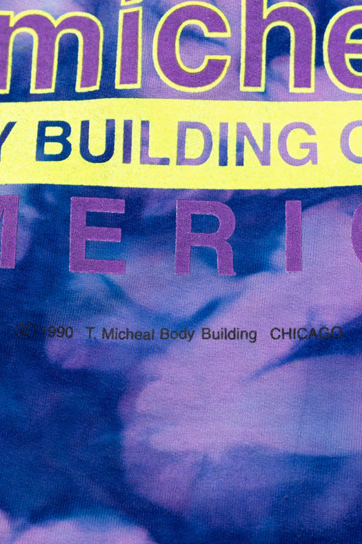 Close-up of a printed graphic with the visible text 'micheal body building america' over a blue and purple abstract background, likely a shirt or fabric print.