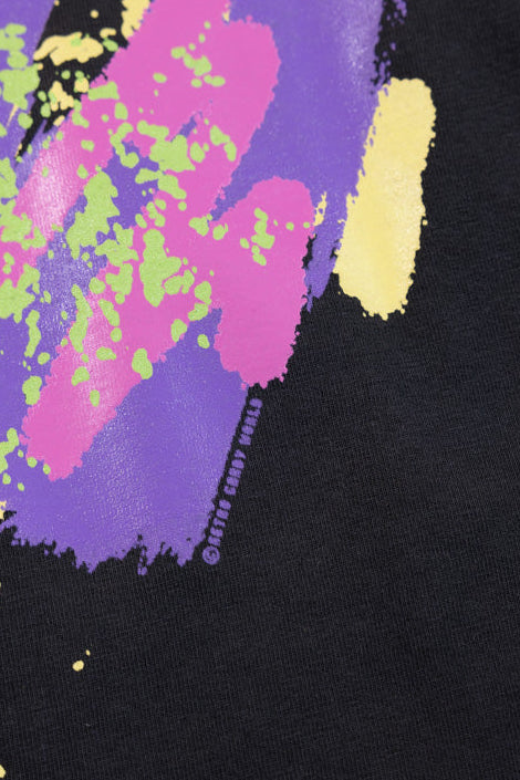 Close-up of Retro Candy World's custom printed black garment featuring a colorful abstract paint-splatter graphic in purple, pink, yellow, and green.
